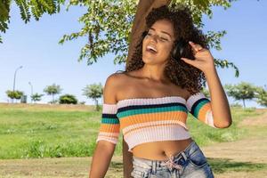 Beautiful afro american girl listening music in a park photo