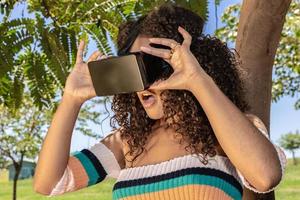 A beautiful young girl plays a game wearing virtual reality glasses on the park. VR headset photo