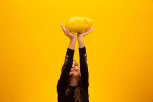 Caucasian little girl over isolated yellow background holding a big piggybank. photo