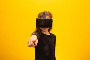 Happy little girl wearing virtual reality goggles watching movies or playing video games. Cheerful smiling teenager looking in VR glasses. Funny child experiencing 3D gadget technology - close up. photo