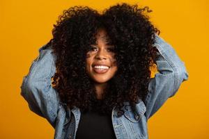 joven mujer afroamericana con cabello rizado mirando a la cámara y sonriendo. linda chica afro con cabello rizado sonriendo mirando a la cámara. foto