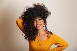 Young afro-american woman with curly hair looking at camera and smiling. Cute afro girl with curly hair smiling looking at camera. photo