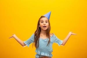 Cute little girl celebrates birthday. Closeup portrait on yellow background. photo