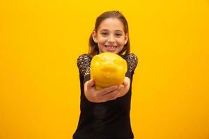 Caucasian little girl over isolated yellow background holding a big piggybank. photo