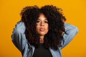 Young afro-american woman with curly hair looking at camera and smiling. Cute afro girl with curly hair smiling looking at camera. photo