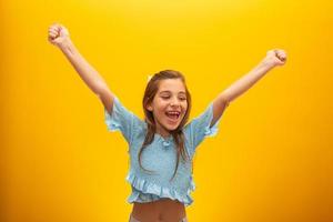 Very happy child celebrating on yellow background. Winner, birthday and gift concept. photo