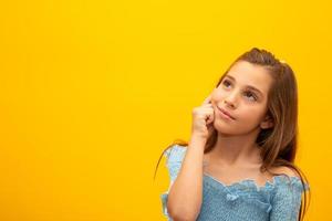 hermoso retrato femenino de medio cuerpo aislado en el fondo amarillo del estudio. pequeña niña brasileña emocional. expresión facial, emociones humanas, concepto publicitario. pensando, mirando hacia arriba. foto