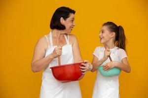 concepto del día de la madre. hija y madre preparando una receta de fondo amarillo foto