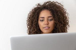 Portrait of smiling young afro american woman holding laptop computer over white background photo