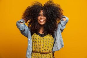 Beauty portrait of african american woman with afro hairstyle and glamour makeup. Brazilian woman. Mixed race. Curly hair. Hair style. Yellow background. photo