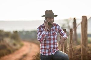 granjero o hombre de campo usando un teléfono inteligente en la granja. agricultor de internet 4g. redes sociales, consultas online. foto