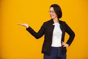 hermosa mujer de negocios de mediana edad sonriendo y mirando a la cámara apuntando con la mano hacia un lado. foto