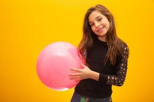 hermosa joven sosteniendo una bola rosa sobre fondo amarillo. foto