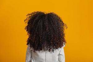joven mujer negra en su espalda con peinado afro sobre fondo amarillo. chica con peinado africano. foto de estudio