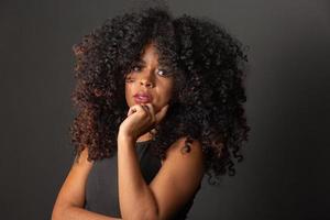 joven mujer afroamericana con cabello rizado mirando a la cámara y sonriendo. linda chica afro con cabello rizado sonriendo mirando a la cámara. foto