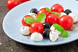 Fresh salad with cherry tomatoes, basil, mozzarella and black olives.