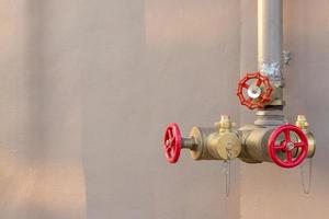 Red valve with pipe near the wall. photo