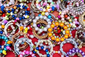 A close-up background of numerous bracelets made of colorful beads. photo