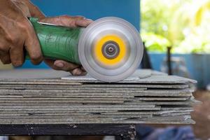 A craftsman is using a grinder to cut into many old ceiling plates. photo