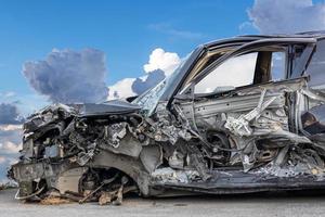 A close-up shot of the front of a black-bronze car destroyed in a collision with another vehicle. photo