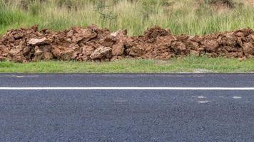 Asphalt road surface with a pile of dirt. photo