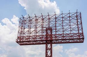 una vista de un letrero antiguo, una estructura de acero rojo que se eleva en anticipación de un anuncio. foto