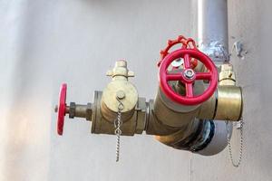 Red valve with pipe near the wall. photo