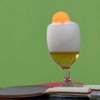 Bubbles of beer in a glass with a ping pong ball. photo