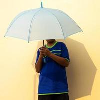 vista de primer plano de un joven tailandés con una camiseta azul sosteniendo un paraguas azul. foto