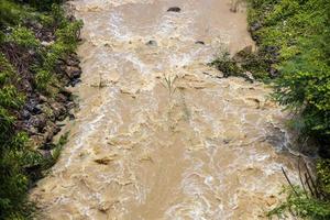 vista superior el agua salvaje fluye violentamente a través de las rocas y los arbustos. foto