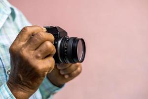 Both hands of an elderly Thai man holding an old film camera. photo