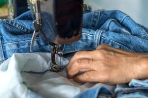 reparar jeans con una vieja máquina de coser. foto