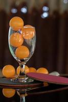 Close-up shot of orange ping pong in clear glass. photo