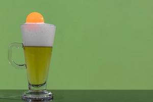 Bubbles of beer in a glass with a ping pong ball. photo