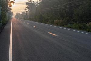 carretera asfaltada con sol naciente en el campo.
