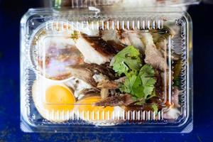 Close-up top view of pork leg rice in a clear plastic box. photo