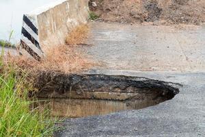 Deep hole under the paved road near the bridge. photo