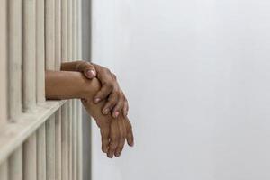 Female prisoner hand on white iron cell bars. photo