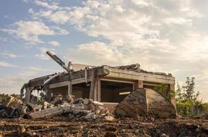 Low view of the ruins of a building with a military-patterned tent. photo