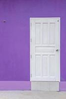 puerta de madera blanca con muro de hormigón morado. foto