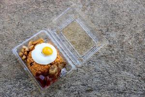 Fried egg fried rice with fried chicken in transparent plastic box. photo