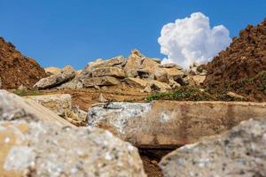 A view of the rubble of concrete blocks obtained from demolition of an old road is laid near a mound. photo