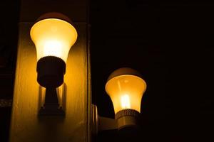 Yellow light bulb with pole in dark room. photo