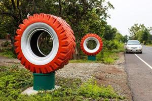 Large tires painted in orange and white decorate the roadside. photo