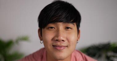 Closeup face of Smiling attractive man looking at camera sit relaxed on couch at home. Webcam view 20s young male holding video call in living room. Video conference event concept.