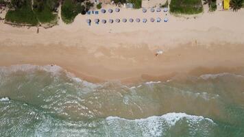 vista aerea della spiaggia di sabbia bianca e della superficie dell'acqua. onde spumeggianti con il cielo. bellissima spiaggia tropicale. incredibile costa sabbiosa con onde bianche del mare. natura, paesaggio marino e concetto estivo. video