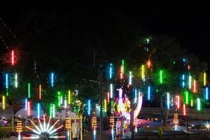 luces de neón colgando de las ramas en el festival. foto
