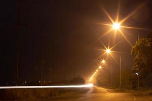 Lighting lamps and car lights on country roads at night. photo