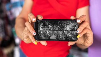 Hand holding a mobile phone extended to see the video checking the CCTV cameras in the shop. in the shop. photo