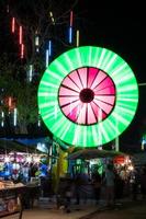 luces de colores giran sobre las tiendas de personas. foto